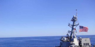 Naval destroyer sailing on open sea with flag flying