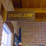 Grand jury sign in a brick-walled hallway