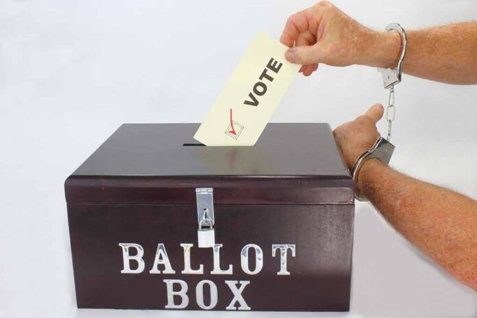Hand in handcuffs casting a vote into a ballot box