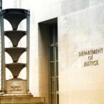 Department of Justice building exterior with sign and metal sculpture