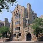 Historic university building with stone facade and surrounding trees