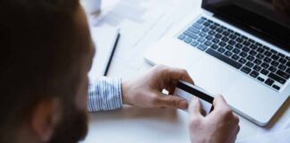 Person holding a credit card near a laptop