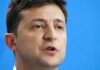 Volodymyr Zelensky speaking in a close-up portrait against a blue background