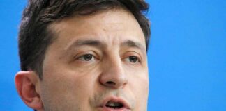 Volodymyr Zelensky speaking in a close-up portrait against a blue background
