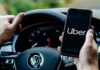 Driver holding smartphone with Uber app inside Volkswagen
