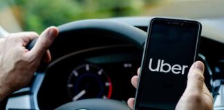 Driver holding smartphone with Uber app inside Volkswagen