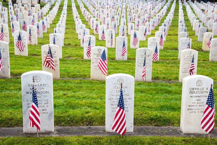 Rows of grave markers adorned with American flags in a military cemetery