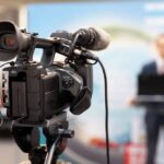 video camera filming a speaker at a podium