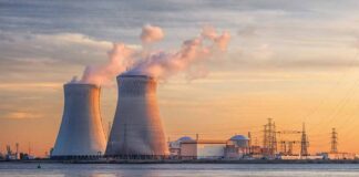 Nuclear power plant with cooling towers emitting steam at sunset
