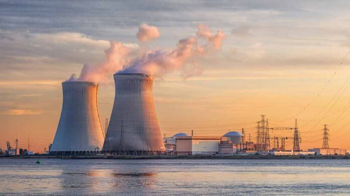 Nuclear power plant with cooling towers emitting steam at sunset