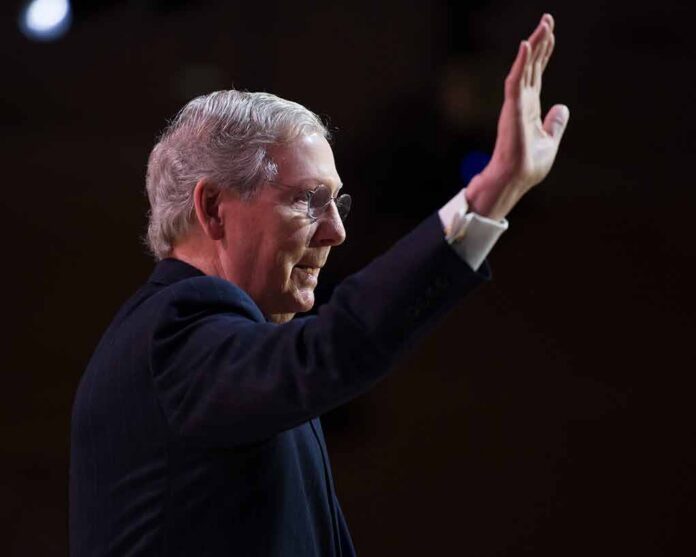 older man in suit raising his hand