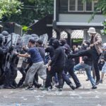 Protesters clash with riot police holding shields