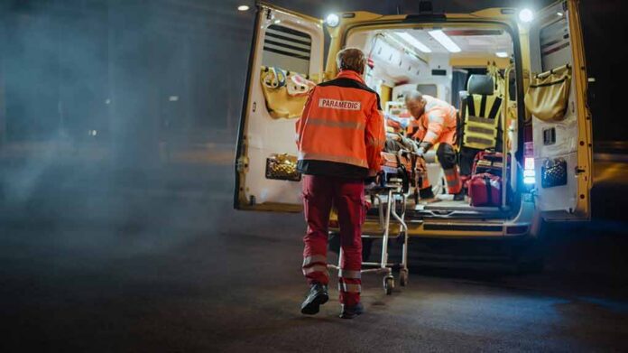 Paramedics load a patient into an ambulance at night