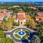 Aerial view of a campus building with red-tile roofs and a round fountain plaza