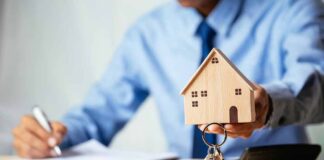 Hand holding a wooden house model with keys