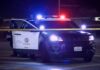 Police SUV with flashing lights at night behind yellow tape