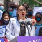 Woman speaking at outdoor podium with microphones
