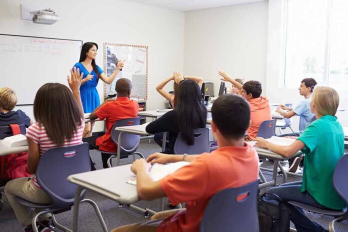 Teacher leading classroom discussion with students raising hands