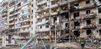 Damaged apartment building behind a playground slide