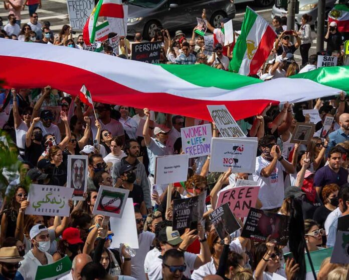 shutterstock_2208976937 Protest crowd with flags and signs; Seyed Ebrahim Raisi, La Parka, Brian Robiskie, Philly Brown, Miguel Francisco Barragán Andrade present