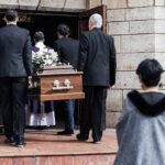 Pallbearers carry a casket into a stone church