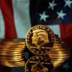 Gold commemorative coins stacked with a profile portrait in front of a U.S. flag