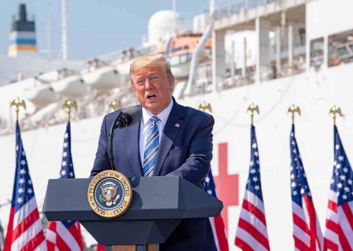 Donald Trump speaking at a podium with American flags and a ship in the background