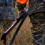 Hunter’s Shot Drops Mom – ‘Thought It Was Deer’ Hunter in camouflage holding a rifle in tall grass