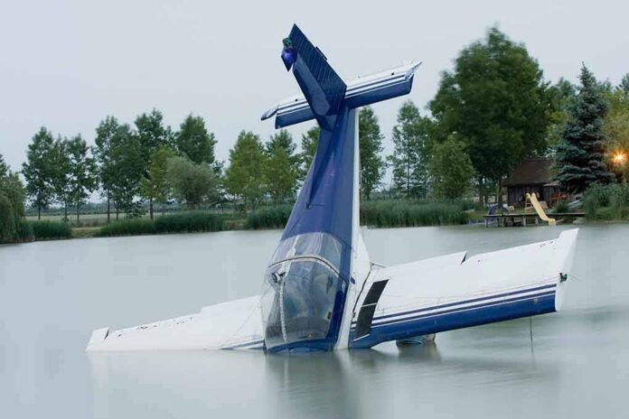 A submerged airplane partially in a lake with trees in the background