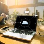 Laptop on desk showing cloud network icons