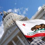 Court Bombshell Triggers California Showdown California state flag in front of a white domed capitol building