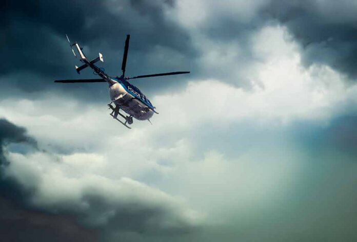 Police helicopter flying under dark storm clouds
