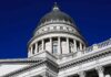 Capitol building dome with columns against a deep blue sky
