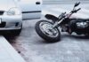 Motorcycle lying on the street beside a car with an open door