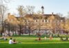 Students relaxing on a campus quad in front of a brick academic building