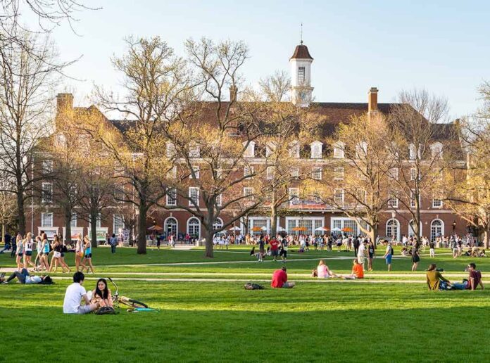 Students relaxing on a campus quad in front of a brick academic building