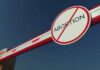 Barrier arm with no abortion sign against blue sky