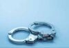 Metal handcuffs on a light blue surface