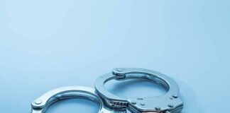 Metal handcuffs on a light blue surface