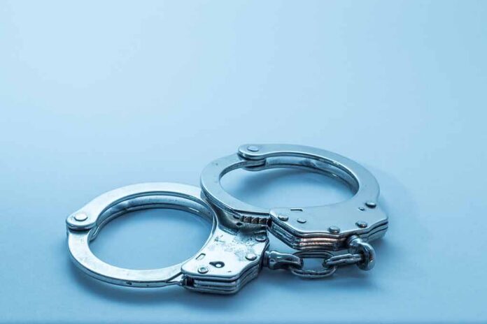 Metal handcuffs on a light blue surface