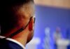 Threat Wave Overwhelms Secret Service Security guard with earpiece watching a blurred event stage
