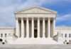 Front view of the Supreme Court building with large columns and steps under a blue sky