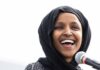 DOJ Raid Sparks Omar Citizenship Storm Ilhan Omar smiling while speaking at a microphone