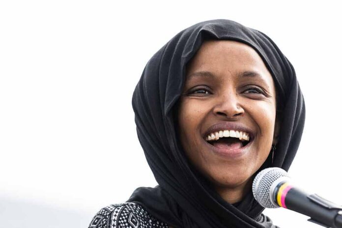 Ilhan Omar smiling while speaking at a microphone