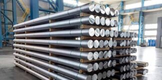 Stacked metal rods on pallets in an industrial warehouse