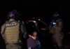 Police officers detain a handcuffed person at night