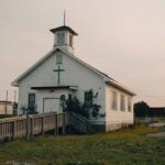 Small white church with steeple and cross at sunset