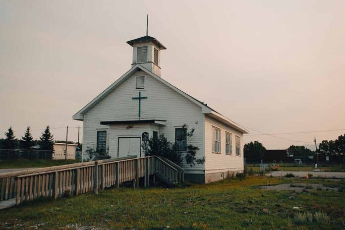 Small white church with steeple and cross at sunset