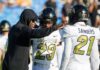 Overtime Thriller Shocks College Football Coach in black hoodie speaks to two football players in white uniforms