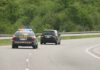 Police car with flashing lights following a minivan on a highway